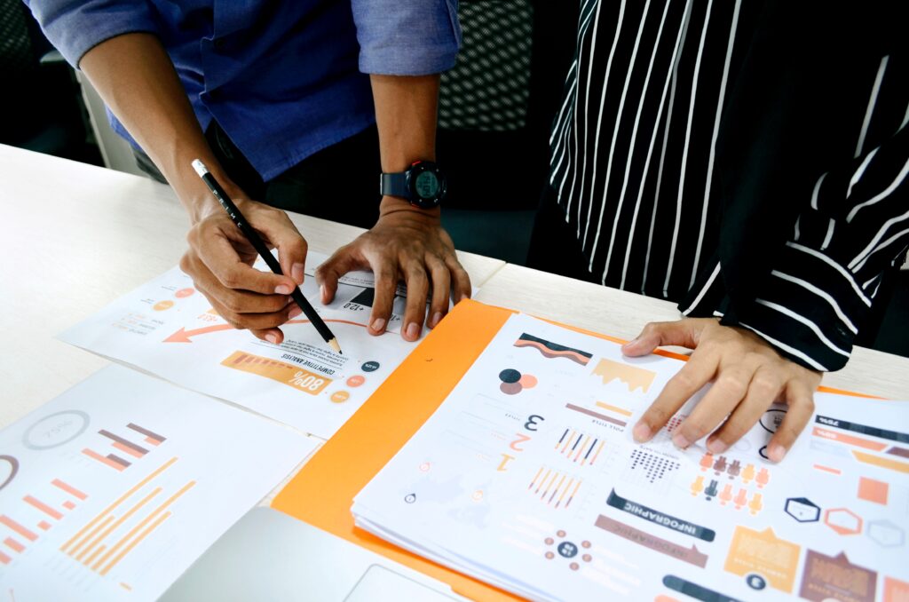 Two people reviewing documents containing various charts and graphs, similar work that a data analyst does