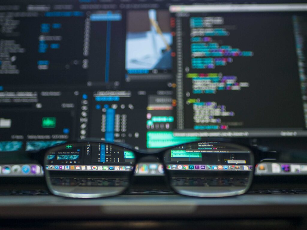 Image of glasses and a computer screen with programming and code language on it